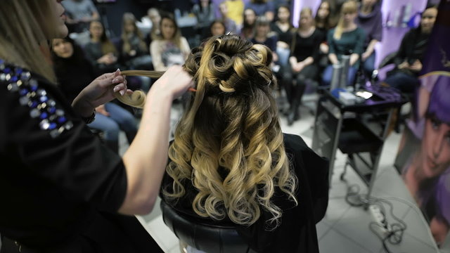 master class in the art of hairdressing, model, and a lot of students of hairdressers in the background.
