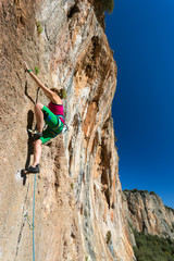 Body of female extreme Climber stepping up on high vertical Rock