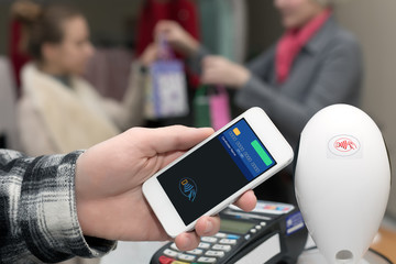 Man completing mobile Payment at Store Cashiers Desk with Terminal