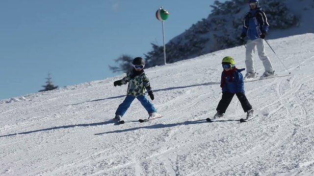 Young family, father and two boys and their uncle, skiing on a sunny day on a mountain summit in Austria resort, winter time