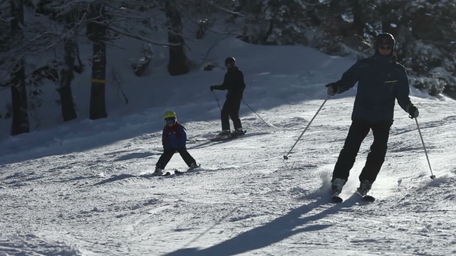 Young family, father and two boys and their uncle, skiing on a sunny day on a mountain summit in Austria resort, winter time