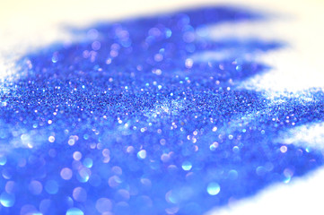 Blurry background of blue glitter sparkles on white surface