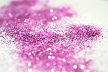 Blurry background of purple glitter sparkles on white surface