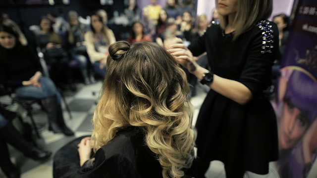 master class in the art of hairdressing, model, and a lot of students of hairdressers in the background.
