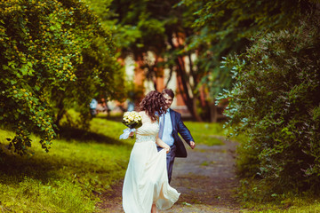 Fototapeta na wymiar Happy newlywed romantic couple walking in the park