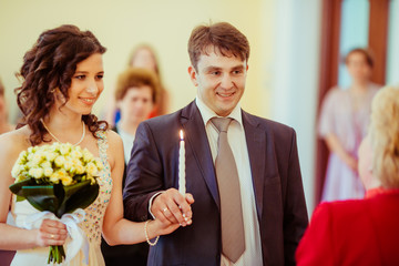 Happy newlywed couple holding candle on wedding ceremony