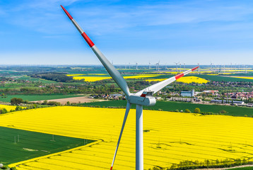 Luftbild und Nahaufnahme einer Windenergieanlage mit einem blühenden Rapsfeld im Hintergrund