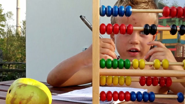 Little boy counting and doing homework outside, zoom out