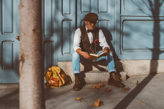 Reading elderly man sitting on the street