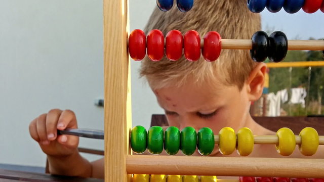 Little boy counting and doing homework outside, zoom out