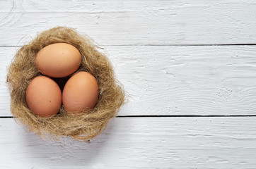 Nest with eggs on white wooden planks background. Easter greeting postcard template. Space for copy, text, lettering.