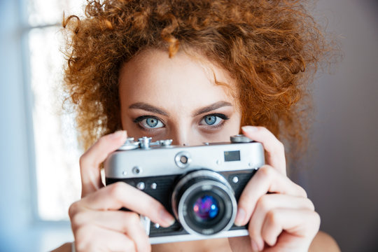 Attractive redhead woman photographer using old camera