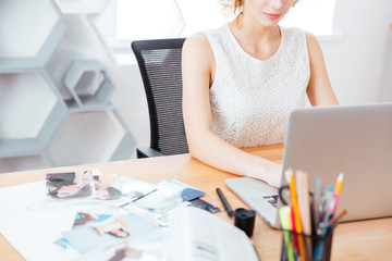 Pretty woman photographer working with laptop in office