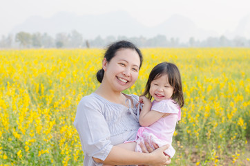 Asian mother and child smiling in flower field