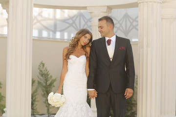 Beautiful bridal couple embracing near columns