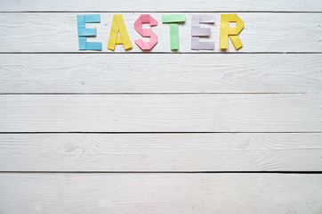 Easter folded paper origami colorful lettering on white wooden planks rustic background. Space for text, copy. Holiday greeting postcard template.