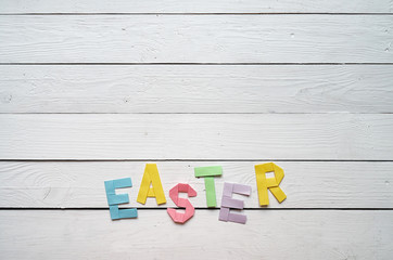 Easter folded paper origami colorful lettering on white wooden planks rustic background. Space for text, copy. Holiday greeting postcard template.