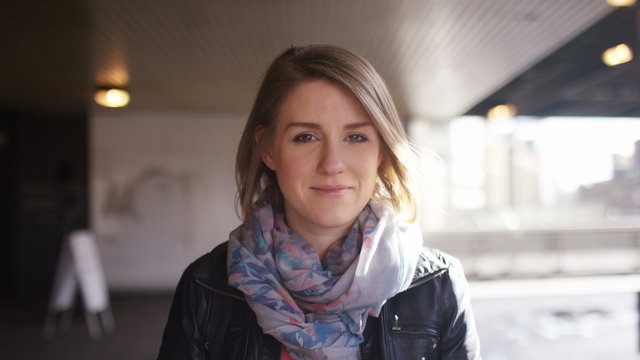 Slow zoom in portrait of an attractive young woman smiling to camera, in slow motion 
