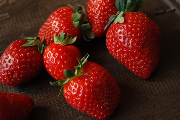 Ripe strawberries on dark brown wooden table, close-up