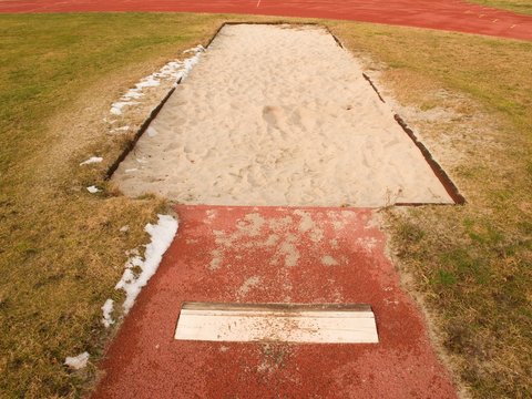 Lane for the long jump. Sandy red retrack, white ake-off board.