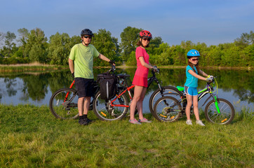 Obraz premium Family bikes ride outdoors, active happy parents and kid cycling and relaxing near beautiful river 