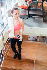 Fototapeta premium Sportswoman listening to music from mobile phone and drinking water