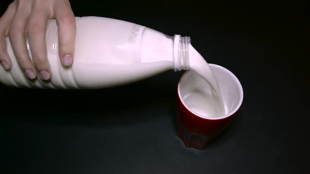 Woman Pours Milk in a Glass of Red White