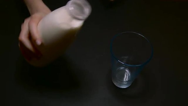 Pouring From a Bottle Into a Glass of Milk