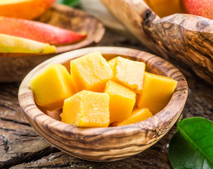 Pieces of mango fruit in the wooden bowl.