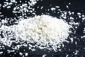 Coconut shreds isolated on black background, selective focus