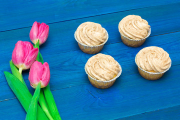 cupcakes with cream and tulips on blue boards