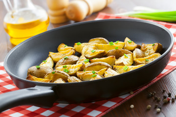 Crispy fried potato wedges on a pan, vegetarian food