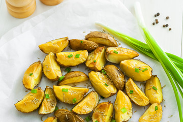 Potato wedges on parchment paper, vegetarian healthy food, top view, close-up