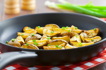 Delicious fried potato wedges on pan, homemade food, close-up