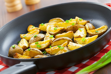 Tasty crispy potato wedges on a pan, vegetarian healthy food, close-up