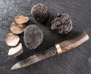 Black truffles and truffle slices on the graphite board.