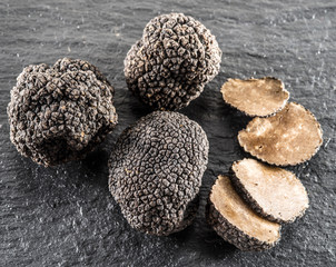 Black truffles and truffle slices on the graphite board.