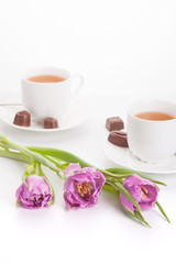 Violet tulips with cups of tea and chocolates