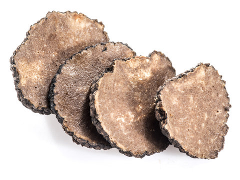 Slices of black summer truffle on a white background.