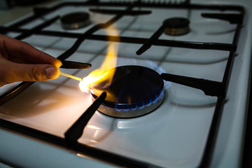 A man lighting the gas stove with a match