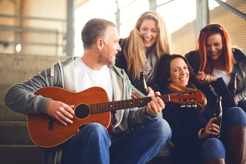 Happy group of friends enjoying playing guitar and singing together