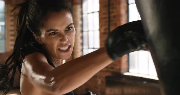 Kickboxing woman training punching bag in fitness studio