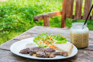 Grilled steak with fresh vegetables and ice coffee