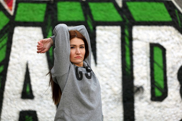 Female hip hop dancer posing in front of a wall with graffiti