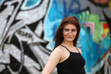 Beautiful girl with red hair standing in front of a wall with graffiti