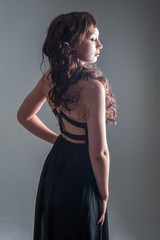 Fototapeta premium Young lady standing with a long black dress and long curly hair 