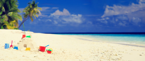 Sand castle on tropical beach and kids toys