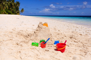 Fototapeta na wymiar Sand castle on beach and kids toys