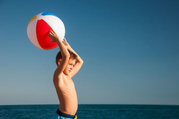 A child playing ball near the sea