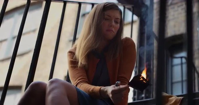 Beautiful sad woman burning photograph of her ex-boyfriend lover